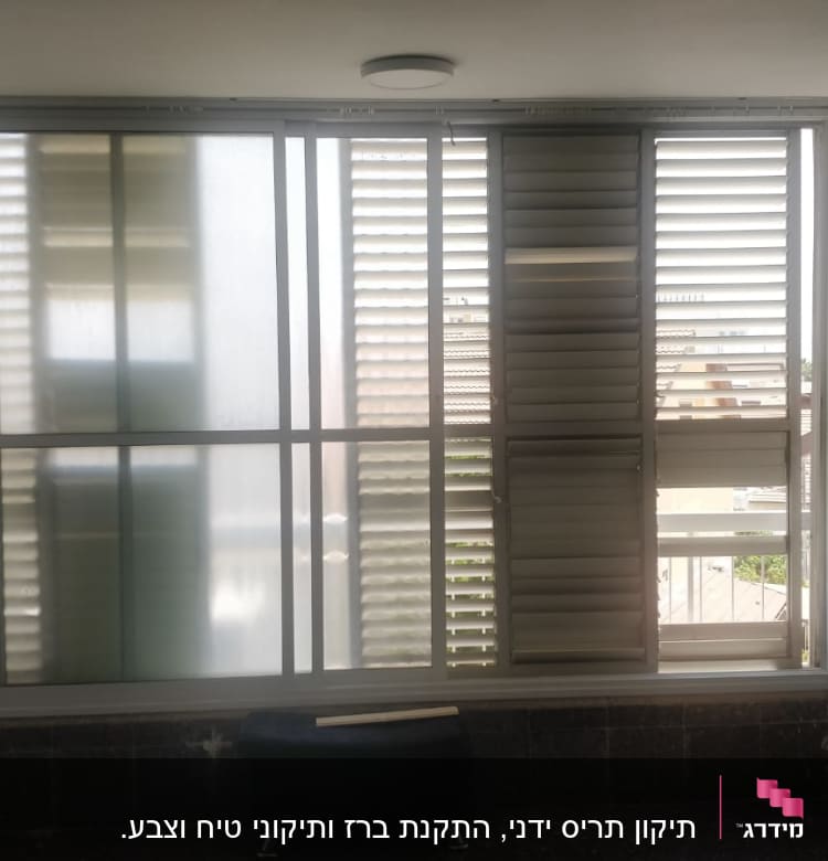 חלון עם תריסים פתוחים וחלקים מונחים על הרצפה